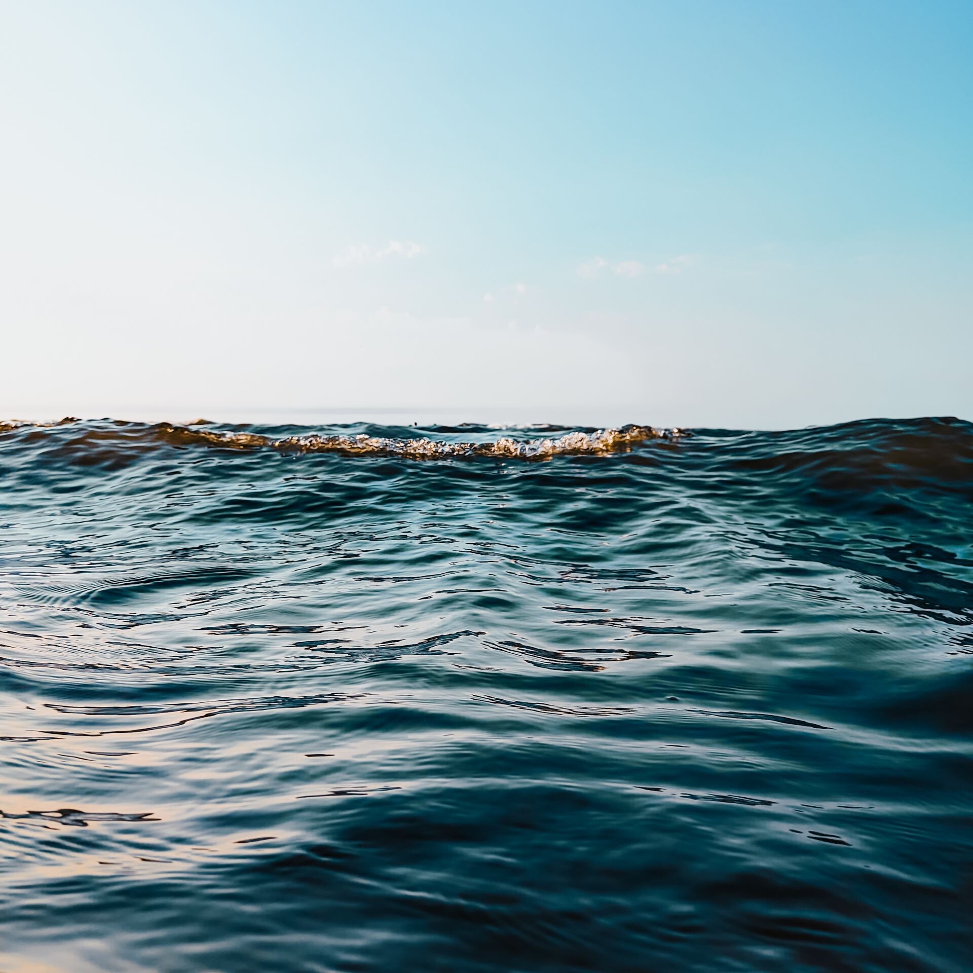 Peaceful ocean waves under a clear sky at sunset in Fereydunkenar, Iran.